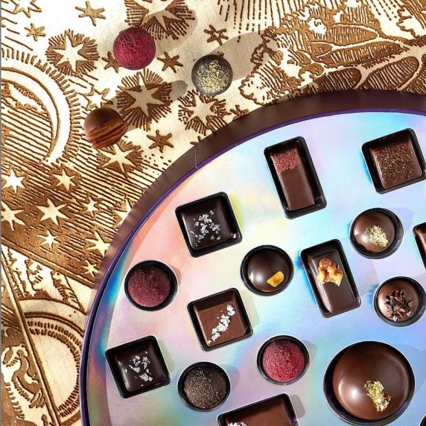 Bonbons in an iridescent-lined round box on a tabletop with a sepia-toned star pattern